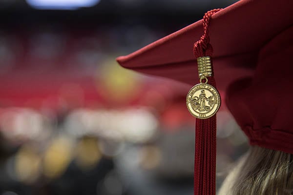 A golden ua seal hangs from a student's mortarboard