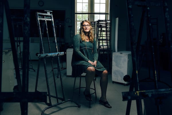 A student sits among easels and art supplies