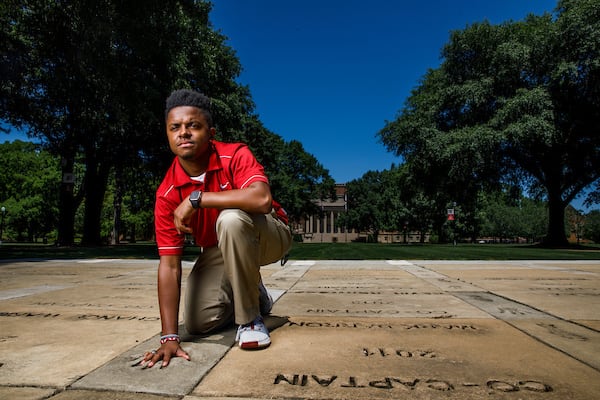 A student places their hand in the concrete handprints that surround denny chimes.