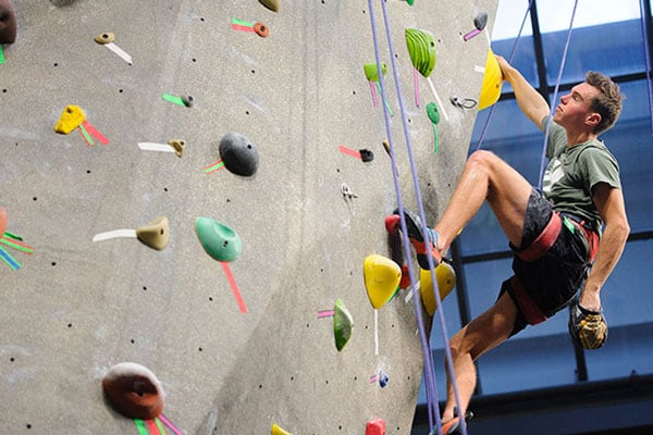 A student scales the rock climbing wall at the Student Recreation Center