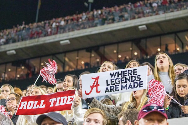 Fans in Bryant-Denny stadium hold up Where Legends Are Made banners